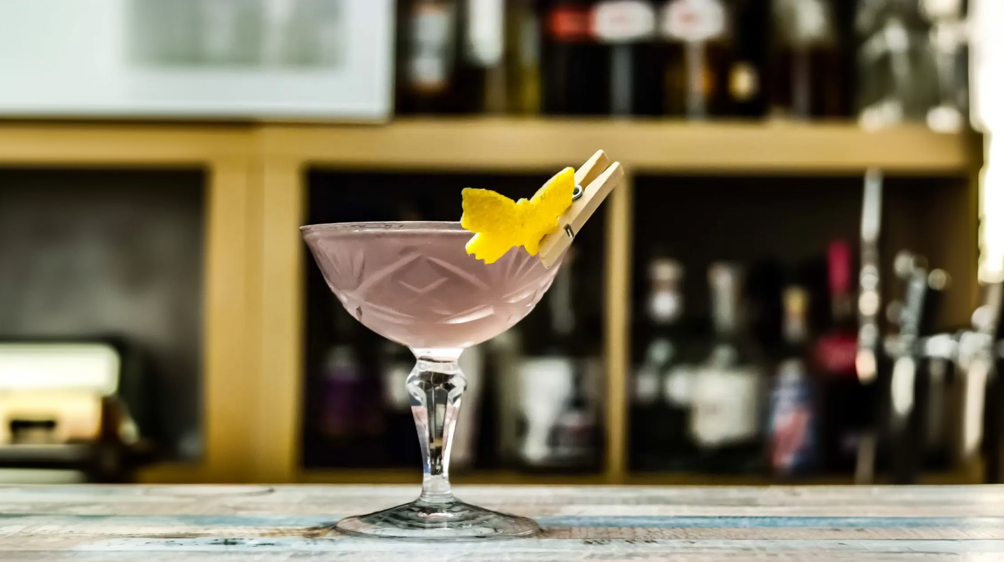 Ein Aviation Cocktail garniert mit einem Zitronenzesten-Schmetterling.