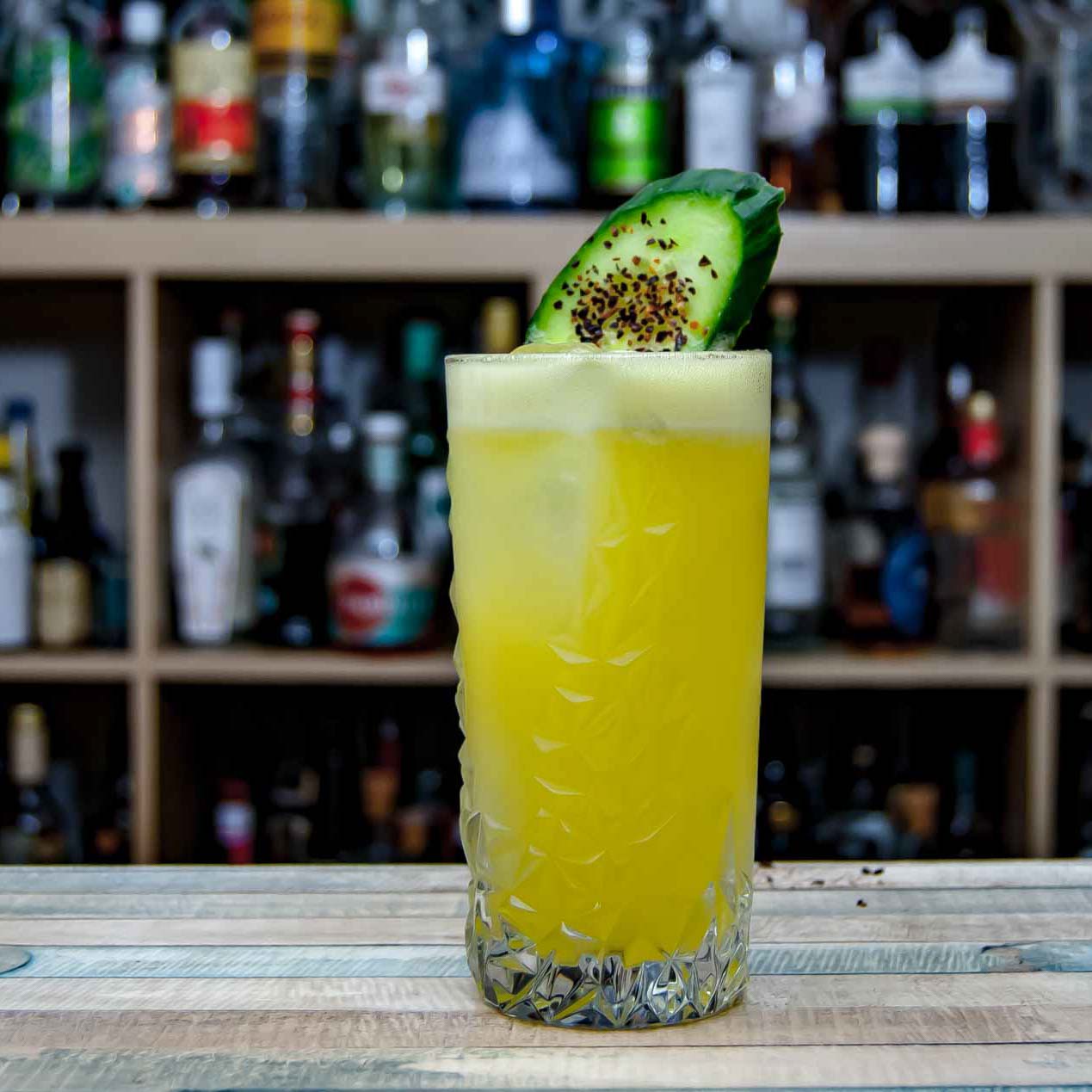 Ein Mezcal Mule, garniert mit Chiliflocken und einer Gurke.