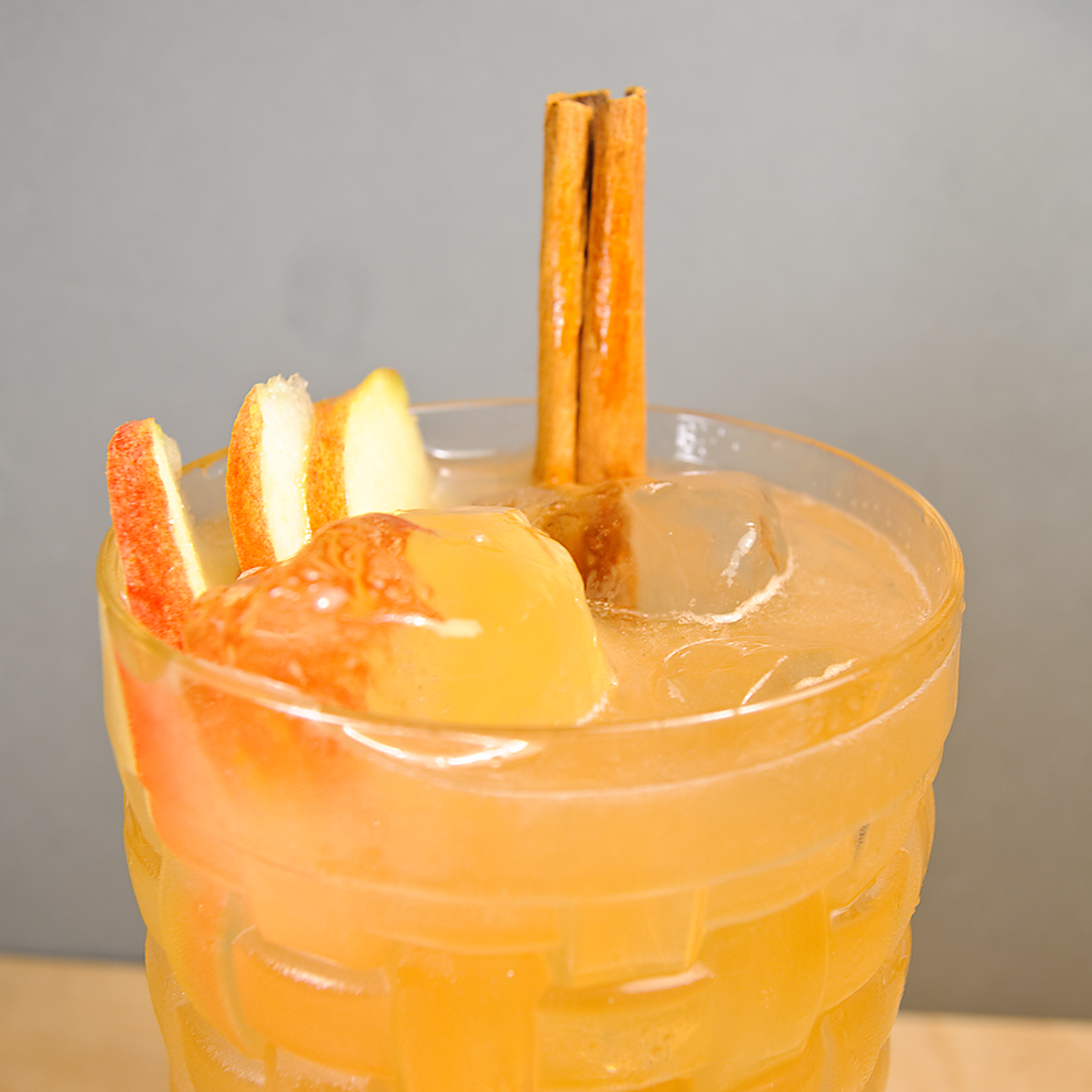 Ein Brazilian Mule aus Cachaca, Apfelsaft, Limettensaft, Vanillelikör und Angostura Bitters, garniert mit Äpfeln und einer Zimtstange.