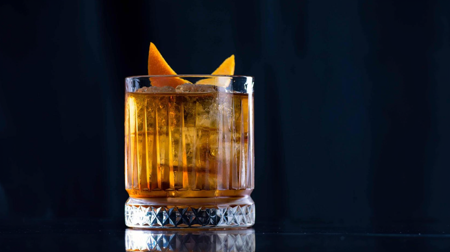 Ein Old Fashioned Cocktail mit Bourbon Whiskey, Bitters, Zuckersirup und Orangenzeste.